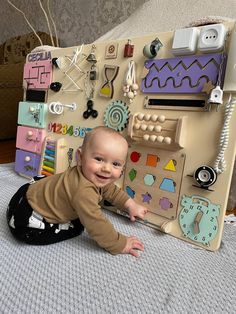 a baby laying on top of a bed next to a wall covered in magnets