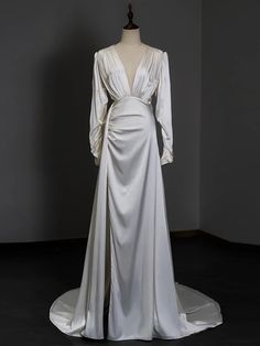 the back of a white wedding dress on display in a room with dark floors and walls