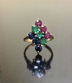 DeKara Designs Classic Handmade Ruby Emerald Sapphire Engagement Ring or Mother's Ring. This ring was entirely handmade and is made to order! Metal- 14K Yellow Gold, .583 Stones- 3 Round Blue Sapphires 0.60 Carats, 3 Round Rubies 0.60 Carats, 3 Round Emeralds 0.60 Carats, 1.80 Total Carats. Art Deco Inspired Sapphire Ruby Emerald Engagement Ring. This ring features three rows of sapphires, rubies, and emeralds that are all round in shape and expertly prong set. High quality stones which are vibr Multicolor 14k Gold Jewelry For Wedding, Elegant Multicolor Ruby Ring, Multicolor Cluster Ring For Anniversary, Multicolor Fine Jewelry Cluster Ring For Anniversary, Yellow Gold Multi-stone Emerald Ring, Yellow Gold Multi-stone Emerald Ring With Round Cut, Multicolor Sapphire Ring In 14k Gold For Wedding, Classic Multi-stone Emerald Wedding Ring, Multicolor Hallmarked Sapphire Ring For Anniversary