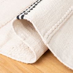 a close up view of the corner of a white rug on a wooden floor with black and white designs