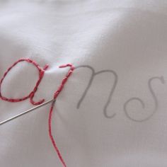 a close up of a sewing needle with the word mom written on it and red thread