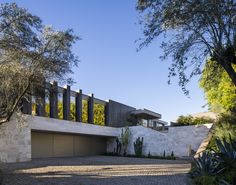 a modern house with large driveway and trees