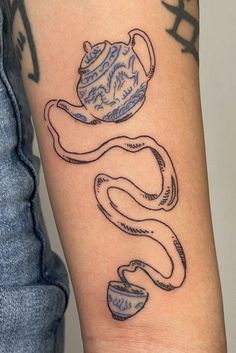 a woman's arm with tattoos on it and an image of a teapot