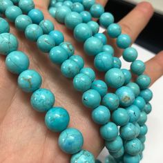 a person holding several turquoise beads in their hand