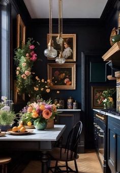 a dining room table with flowers in vases and pictures on the wall behind it