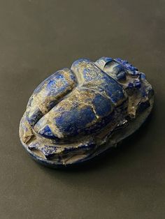 a piece of blue pottery sitting on top of a black surface with peeling paint all over it