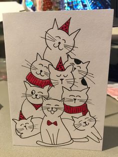 a white card with black and red cats wearing party hats on it's head