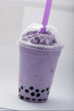 a purple drink with black spots on the rim and a purple straw sticking out of it