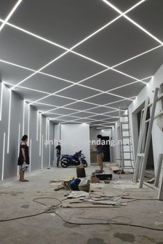 two people are standing in the middle of a room with white walls and ceiling lights