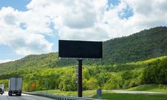 two trucks driving down the road with a large screen on it's back end