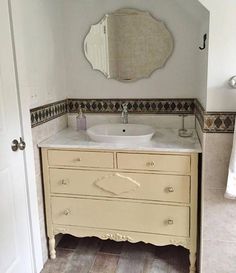 a white sink sitting under a mirror next to a bathroom vanity with a large mirror above it