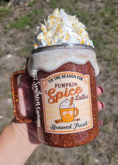 someone holding up a pumpkin spice lager with whipped cream on top and sprinkles