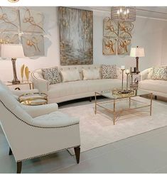 a living room filled with lots of white furniture and gold accents on top of it