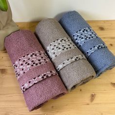 four towels are lined up on a wooden table next to a vase with a plant in it