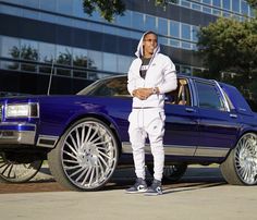 a man standing in front of a blue car