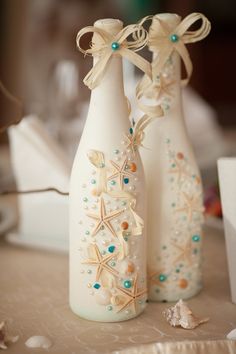 two white vases decorated with seashells and bows are sitting on a table