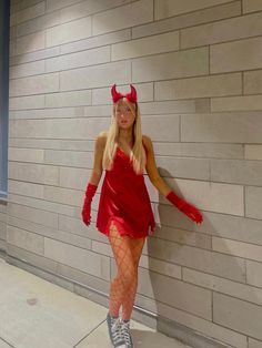 a woman in a devil costume leaning against a wall