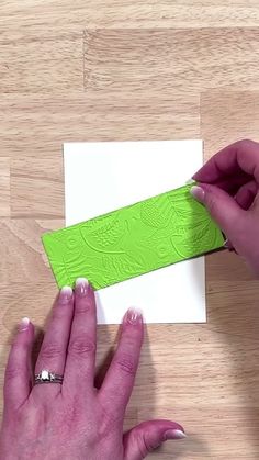 someone is cutting out a piece of paper with a green adhesive tape on it