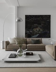 a living room filled with furniture and a large painting on the wall above it's coffee table