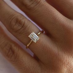 a woman's hand with a diamond ring on top of her finger and an engagement band