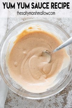 a glass bowl filled with batter on top of a white tablecloth next to a spoon