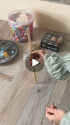 a person holding chopsticks over a wooden table with other items on the table