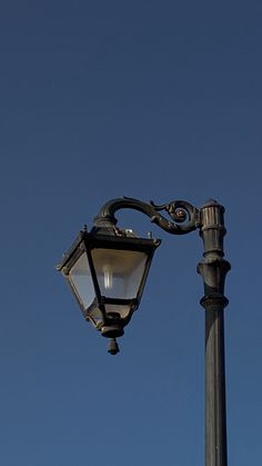 an old fashioned street light on a pole with a clear blue sky in the background