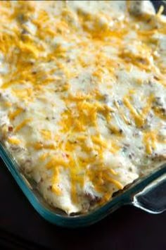 a casserole dish with cheese and meat in it sitting on a black table