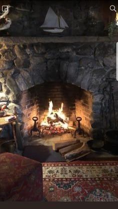 a living room filled with furniture and a fire place next to a stone fireplace covered in logs