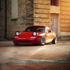 a red sports car parked in front of a brick building