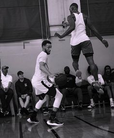 two men are playing basketball while people watch