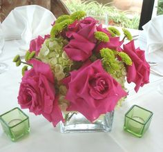 a vase filled with pink and white flowers on top of a table next to candles