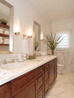 a bathroom with two sinks and a large mirror above the sink is decorated in white marble