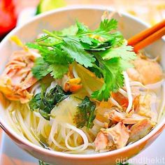 a bowl filled with noodles, meat and veggies next to chopsticks