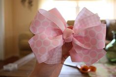 a hand holding a pink bow on top of a table