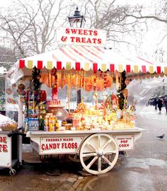 an old fashioned candy cart with sweets and treats on it's stand in the rain