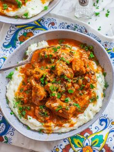 two bowls filled with mashed potatoes and meat in gravy, garnished with parsley