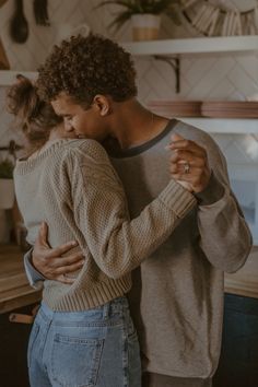 a man and woman hug in the kitchen while holding each other's arms together