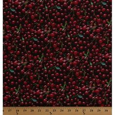 red cherries with green leaves on a black background, in front of a ruler