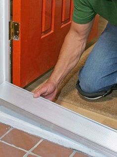 a man kneeling on the floor in front of a red door and opening it with his hands