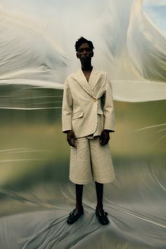 a man standing in front of a painting wearing a white suit and black slippers