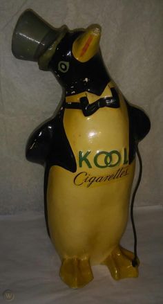 a yellow and black penguin with a hat on it's head is holding a keoligan bottle