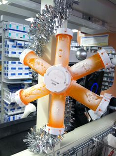 an orange and white clock hanging from a ceiling in a store with silver tinsel