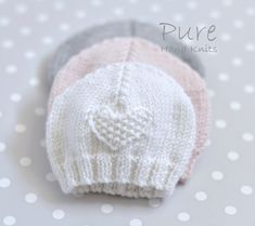 three knitted hats sitting on top of a polka dot table