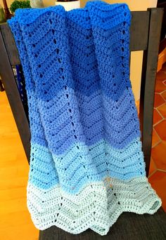 a blue and white crocheted blanket sitting on top of a chair