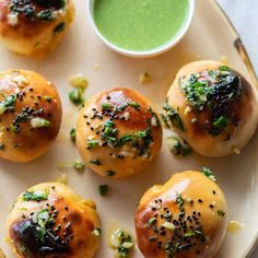 small rolls with green sauce and sprinkles on a plate