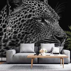 a living room with a couch, table and large leopard wall mural on the wall