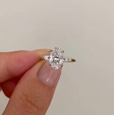 a woman's hand holding an engagement ring in front of her face, with the center diamond on it