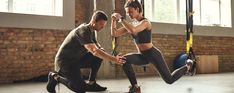 a man and woman doing exercises in a crossfit gym with one holding the other's leg