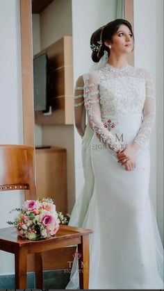 a woman standing in front of a mirror wearing a wedding dress